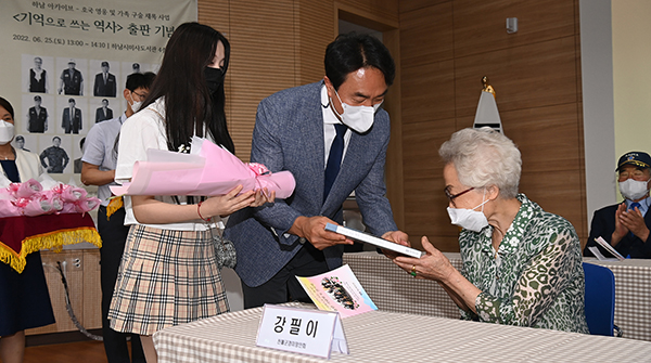김상호 하남시장이 지난 25일 미사도서관에서 열린 ‘기억으로 쓰는 역사 출판 기념회’에 참석해 전몰군경 미망인에게 책자를 전달하고 있다.